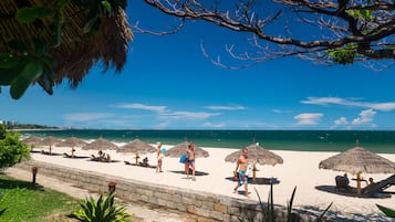 Een privéstrand, wit zand, ligstoelen aan het strand, parasols