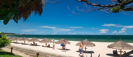 Privat strand, hvit sand, solsenger og parasoller