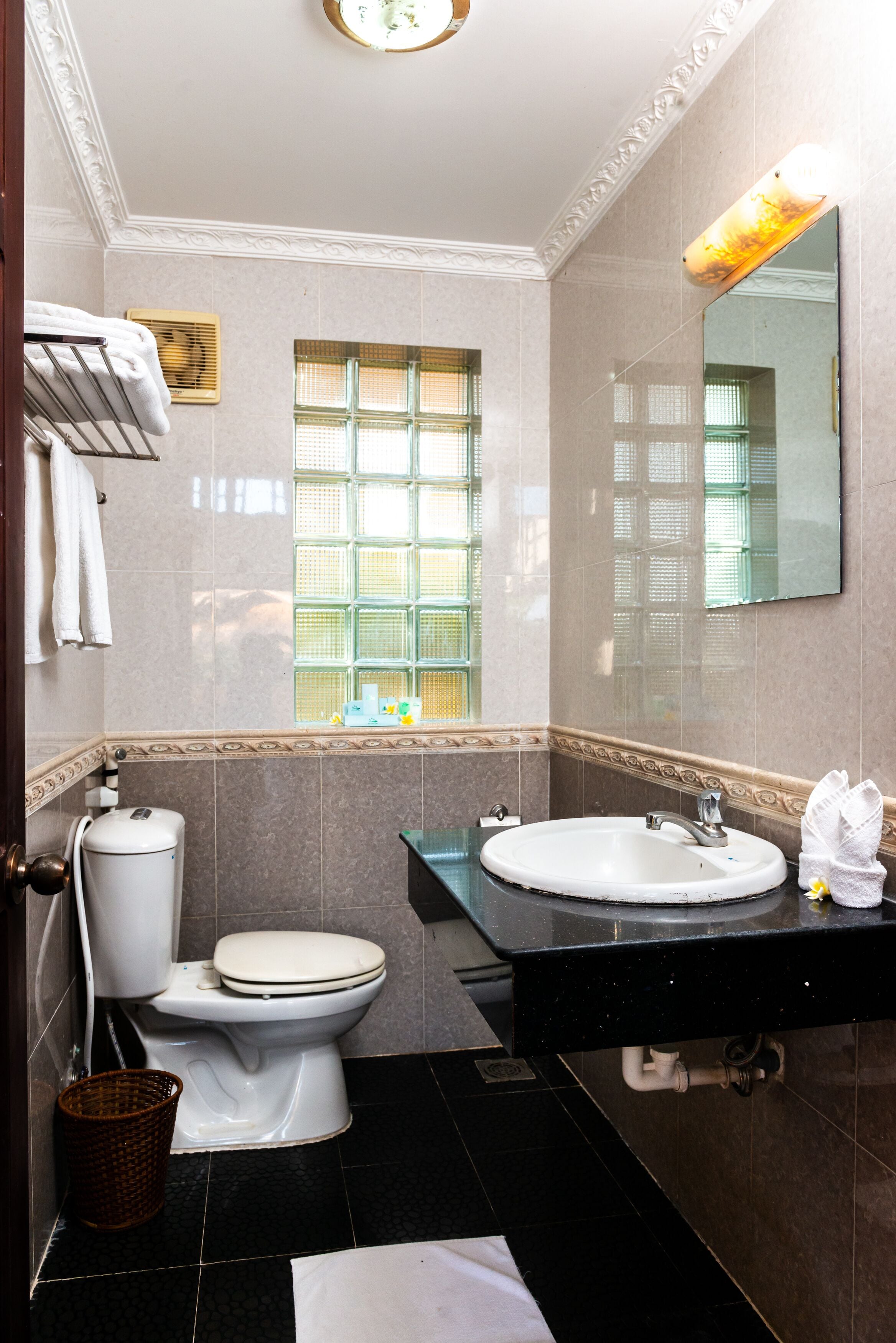 A bathroom with a toilet, sink, and window.