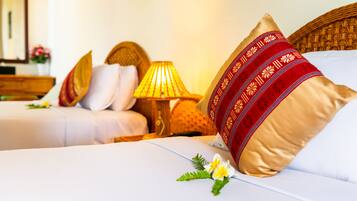 A hotel room with two beds, a lamp, and decorative pillows.