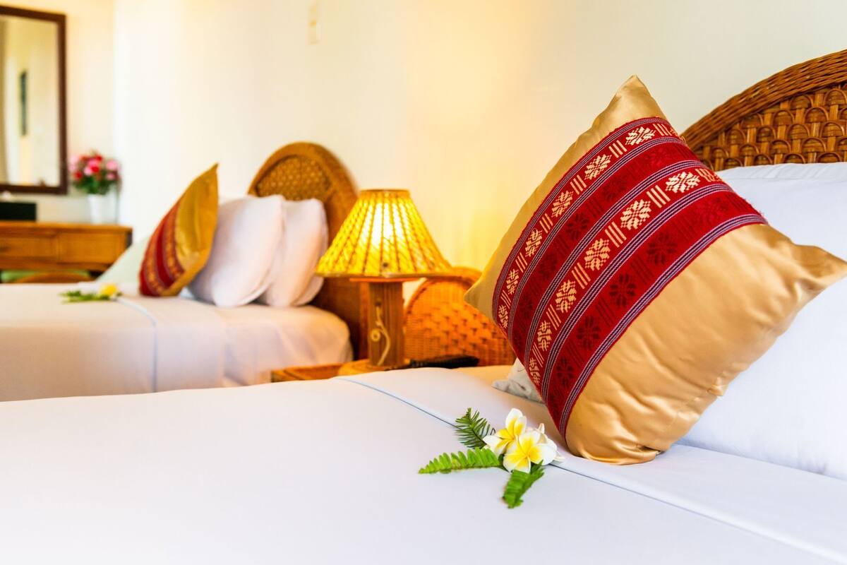 A hotel room with two beds, a nightstand with a lamp, and a mirror.