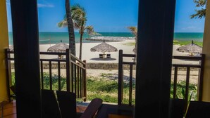A beach view from a balcony with thatched umbrellas and chairs. - White Sand Resort (Phan Thiet)
