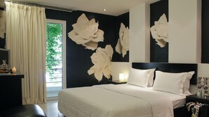 Un dormitorio moderno con una cama grande, una mesita de noche, un escritorio y vistas al verdor exterior.