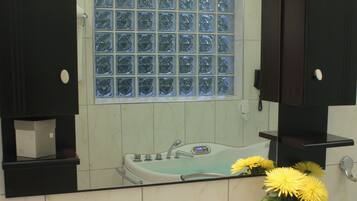 A bathroom with a white sink, a mirror, and a window with frosted glass.