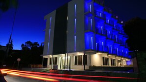 Un edificio moderno con techo plano, varios balcones y una señal de stop al frente.