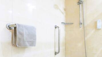 Un baño con ducha, toallero y barra de apoyo.