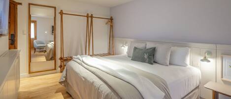 Ein Schlafzimmer mit einem großen Bett, Nachttischen, einem Spiegel und Holzboden.