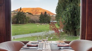 A dining table set for four with a view of a grassy field and a mountain in the background.