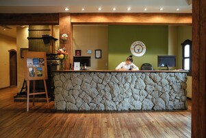 Un mostrador de recepción con fachada de piedra, suelo de madera y un cuadro en un atril.