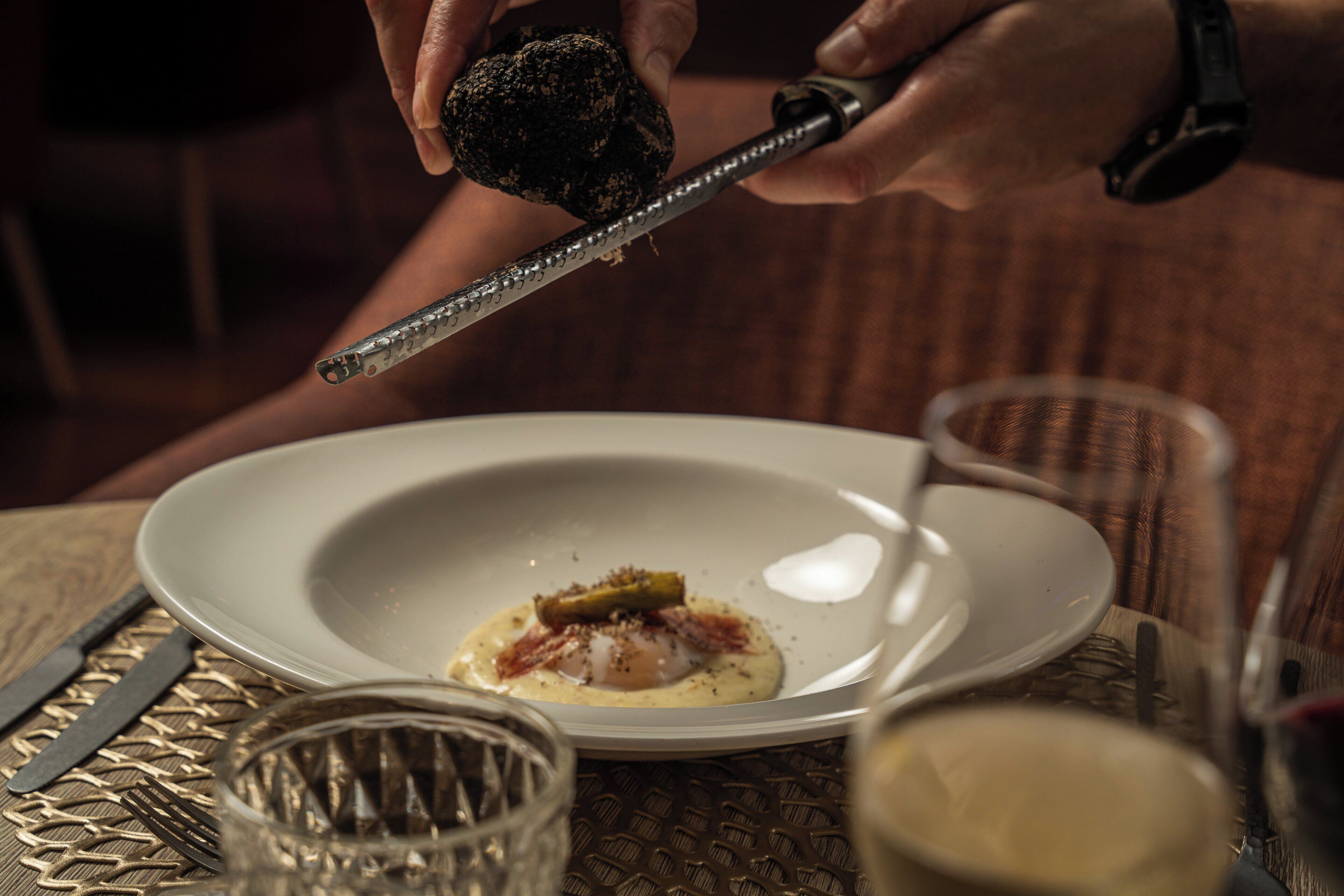 A person using a grater to prepare food on a plate.