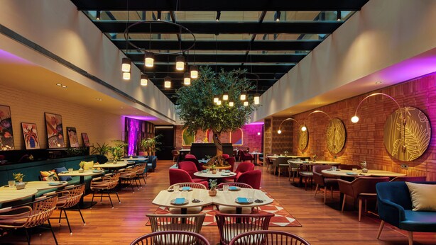 A spacious restaurant with high ceilings, wooden flooring, and a variety of seating options including tables and chairs. - Hotel Indigo Barcelona Plaza Espana by IHG (Barcelona)
