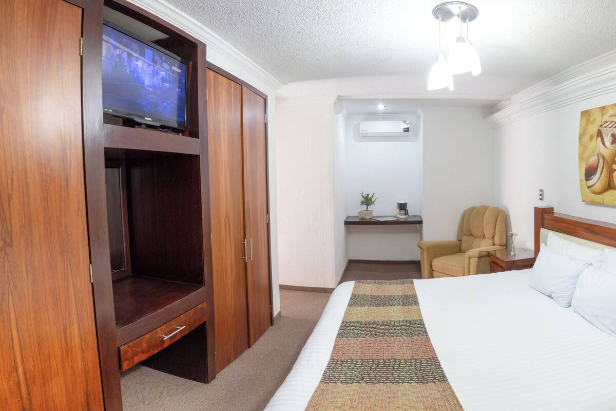 A hotel room with a bed, a TV, a desk, and a chair.