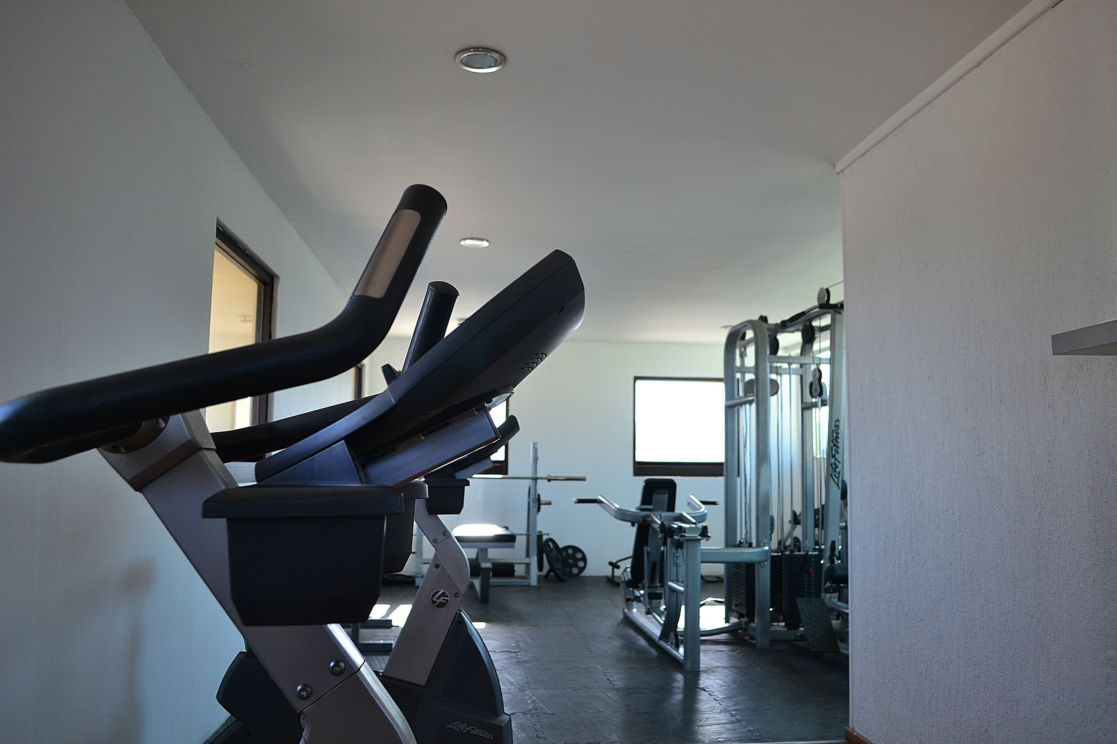 Une salle de sport équipée de matériel d’exercice, notamment un tapis de course et des appareils de musculation.