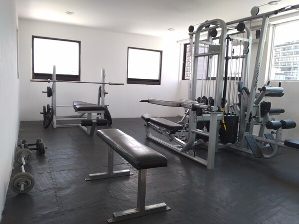 A gym with weightlifting equipment, benches, and treadmills. - Hotel Campestre Inn (León)