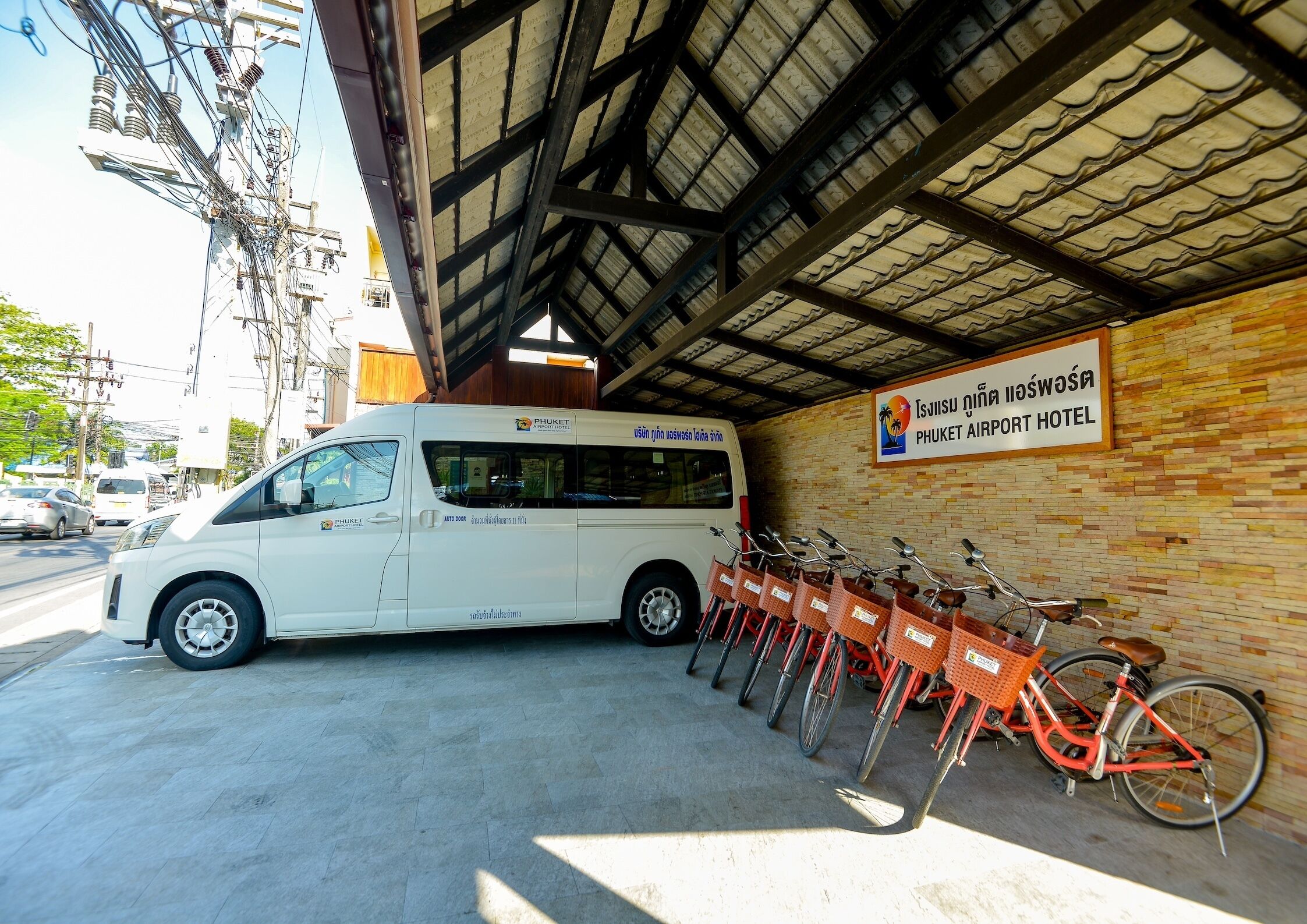 A white van parked under a covered area with a sign for the Phuket Airport Hotel.