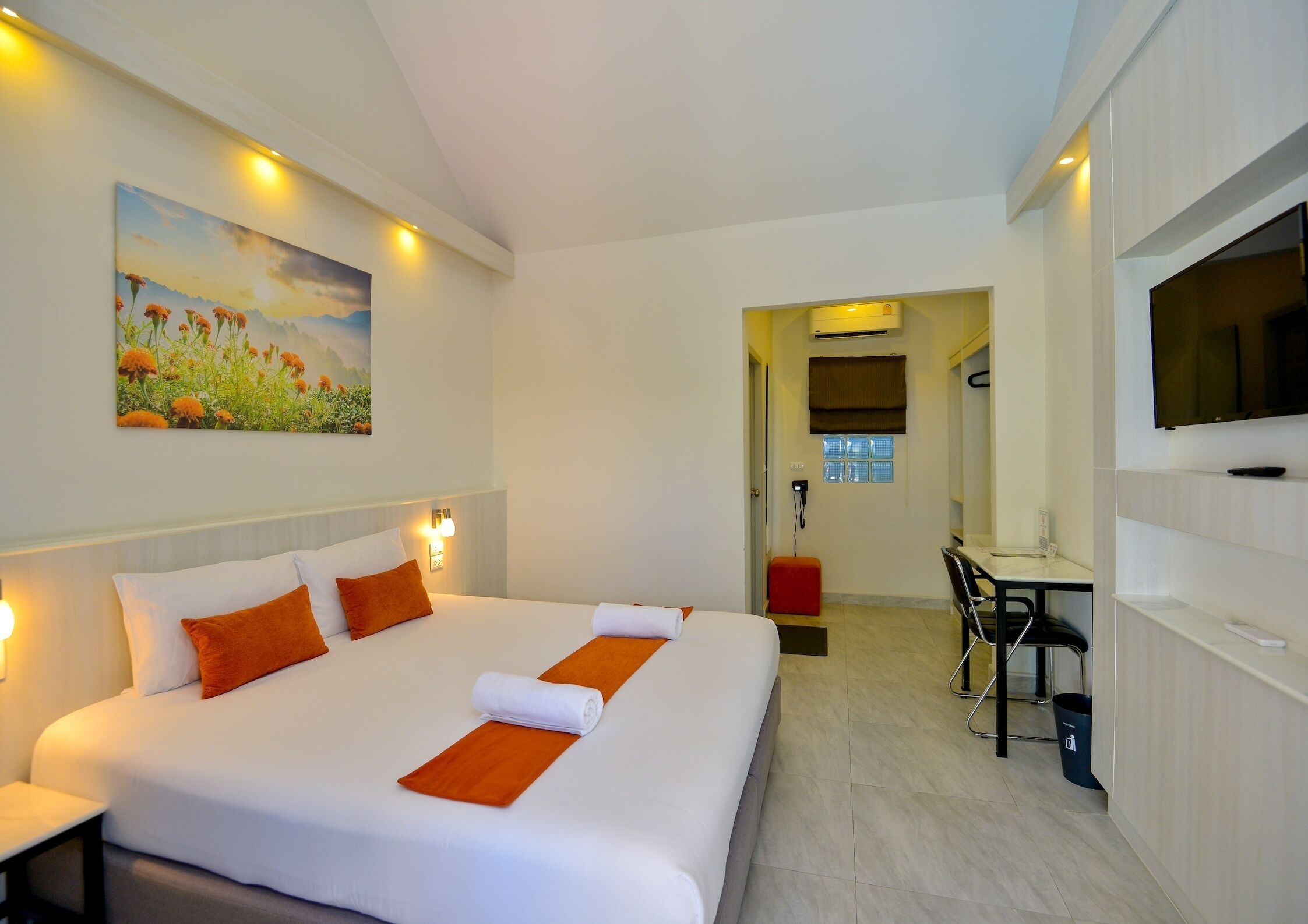 Une chambre d’hôtel avec un grand lit, un bureau, une chaise, une télévision et un tableau au mur.