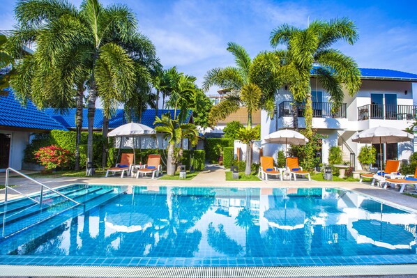 Una piscina al aire libre, sombrillas, sillones reclinables de piscina