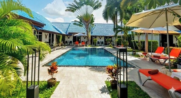 Una piscina al aire libre, sombrillas, tumbonas