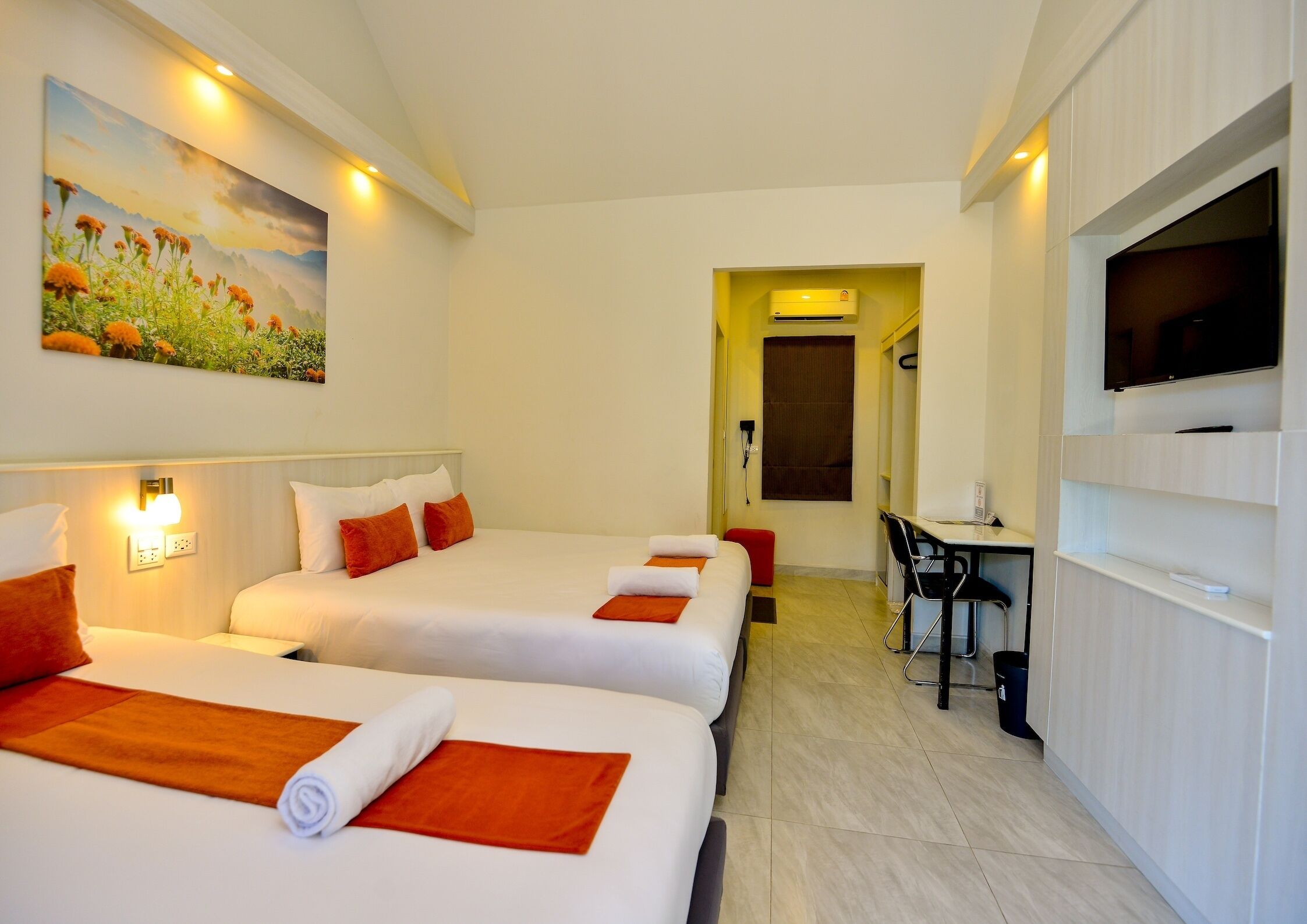 A hotel room with two beds, a desk, a TV, and a painting on the wall.