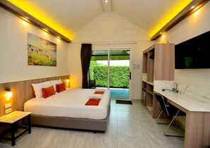 Una habitación de hotel con una cama grande, un escritorio, un televisor de pantalla plana y una puerta corrediza al exterior.