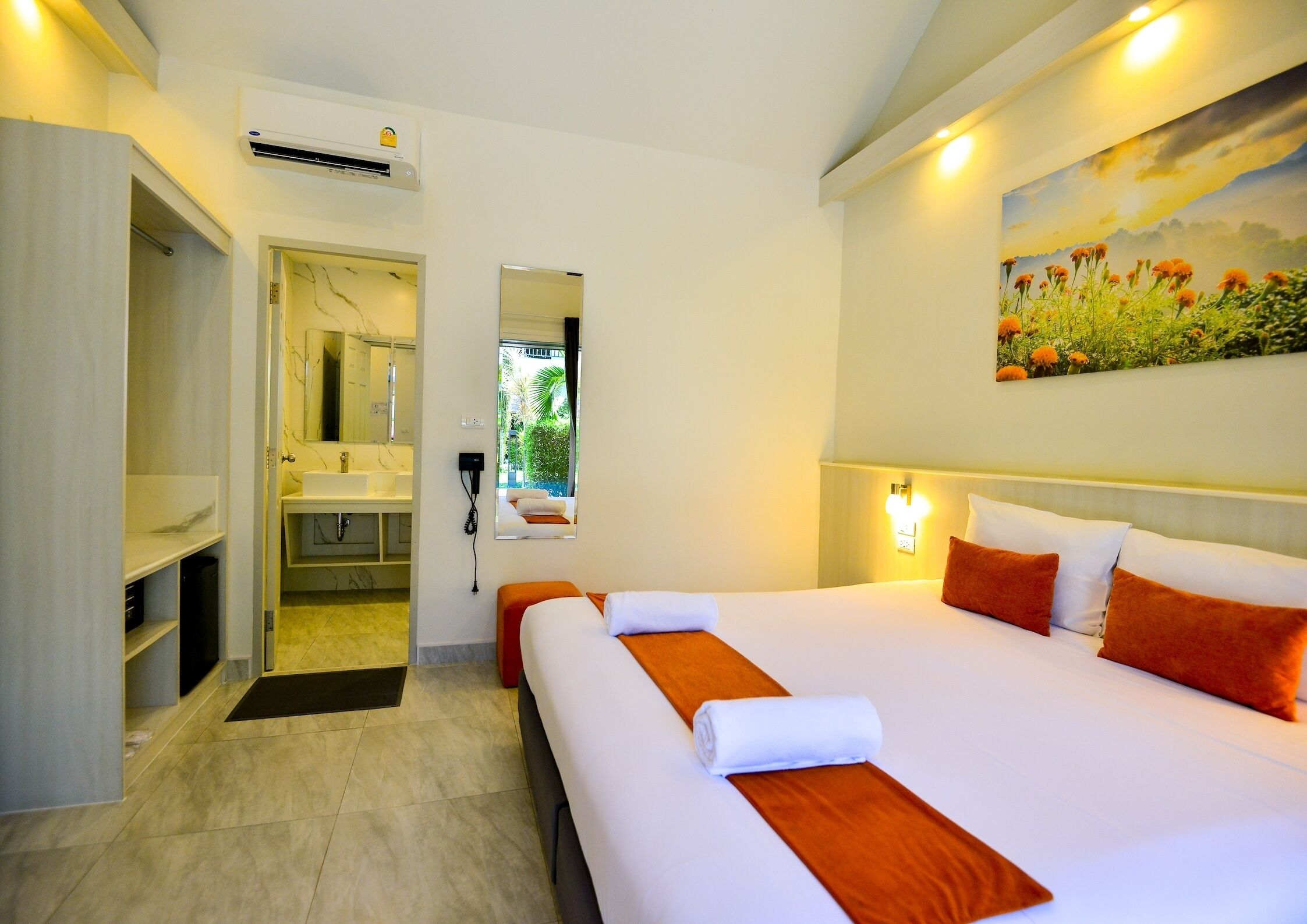 A hotel room with a large bed, a bathroom with a mirror and sink, and a painting on the wall.