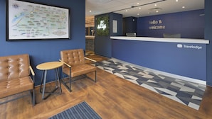 A reception area with a blue wall, a map, a 'hello & welcome' sign, and a TravelLodge logo. - Travelodge Swindon Central (Swindon)