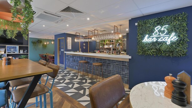 A bar cafe interior with a bar counter, seating area, and a neon sign. - Travelodge Swindon Central (Swindon)