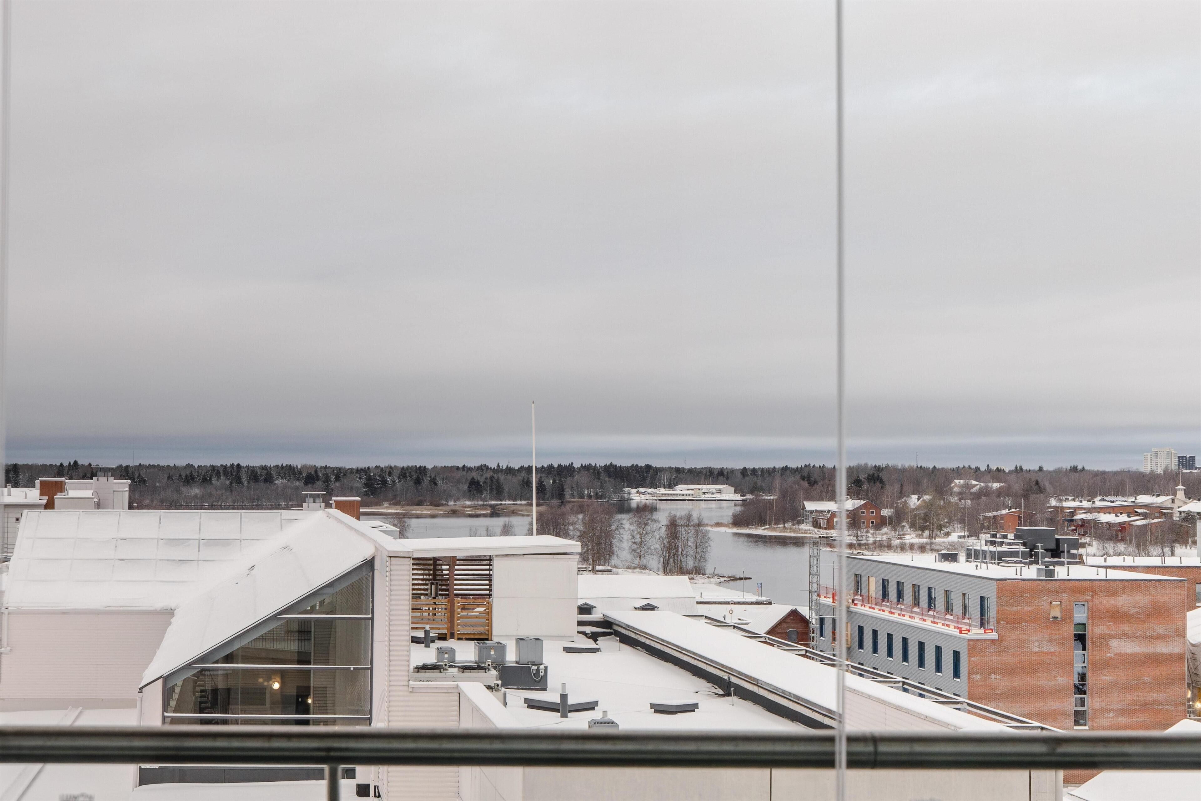 A view of a cityscape with buildings, a river, and a cloudy sky.