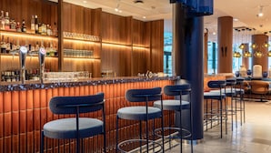 Una zona de bar con taburetes, una barra y estanterías llenas de botellas.