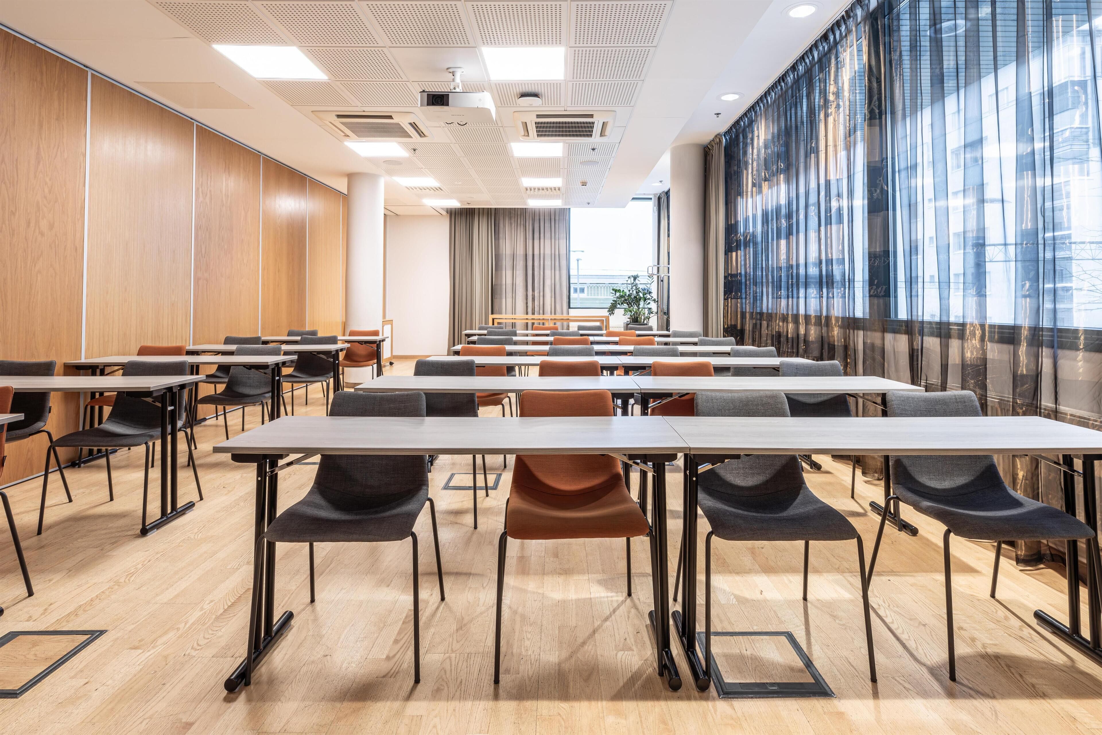 Uma sala de conferência com mesas, cadeiras, janelas amplas e um design moderno no teto.