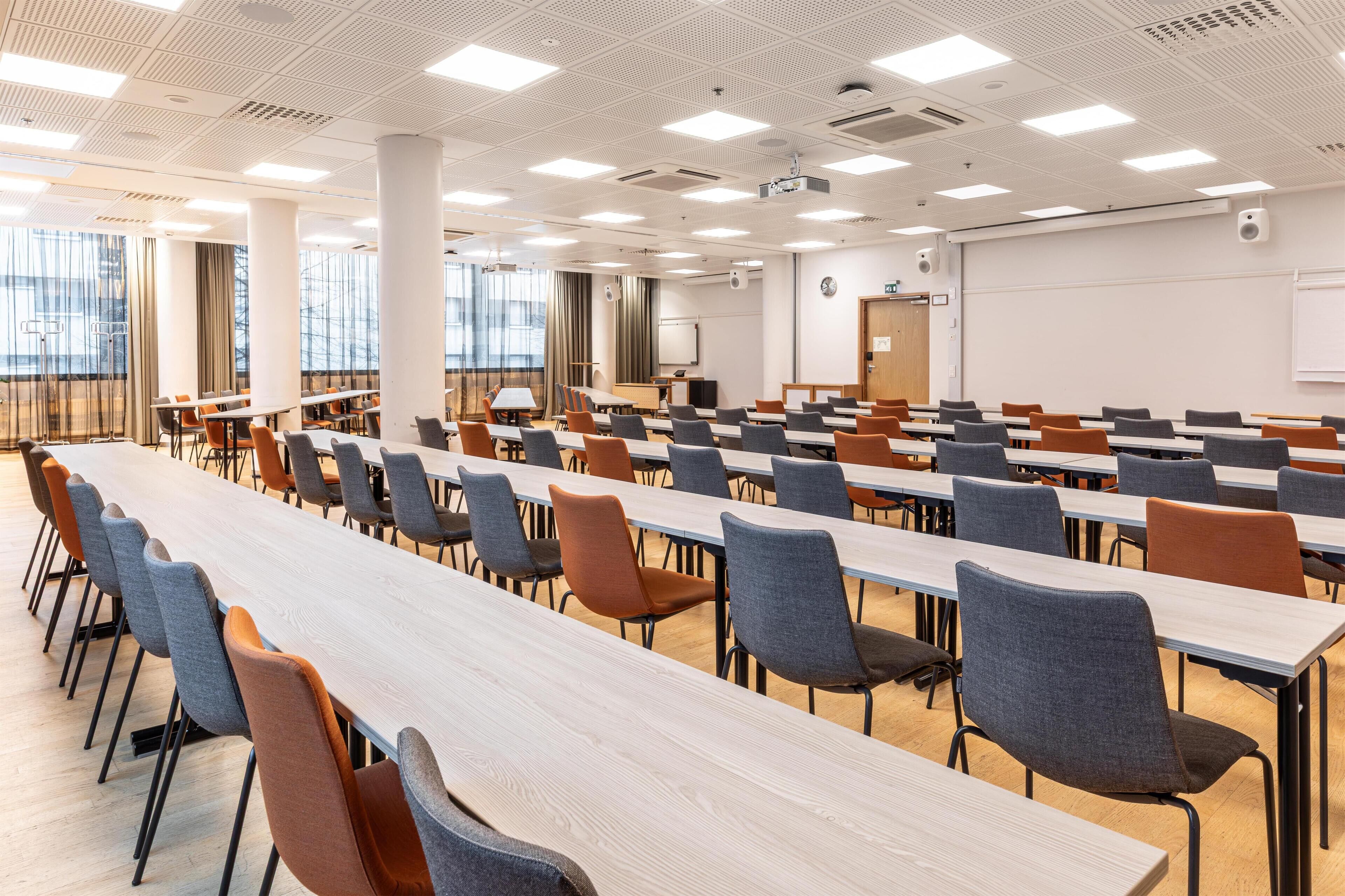A conference room with long tables and chairs, large windows, and a whiteboard.