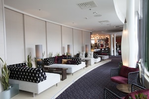 A modern hotel lobby with seating areas, a bar, and a view of the interior.