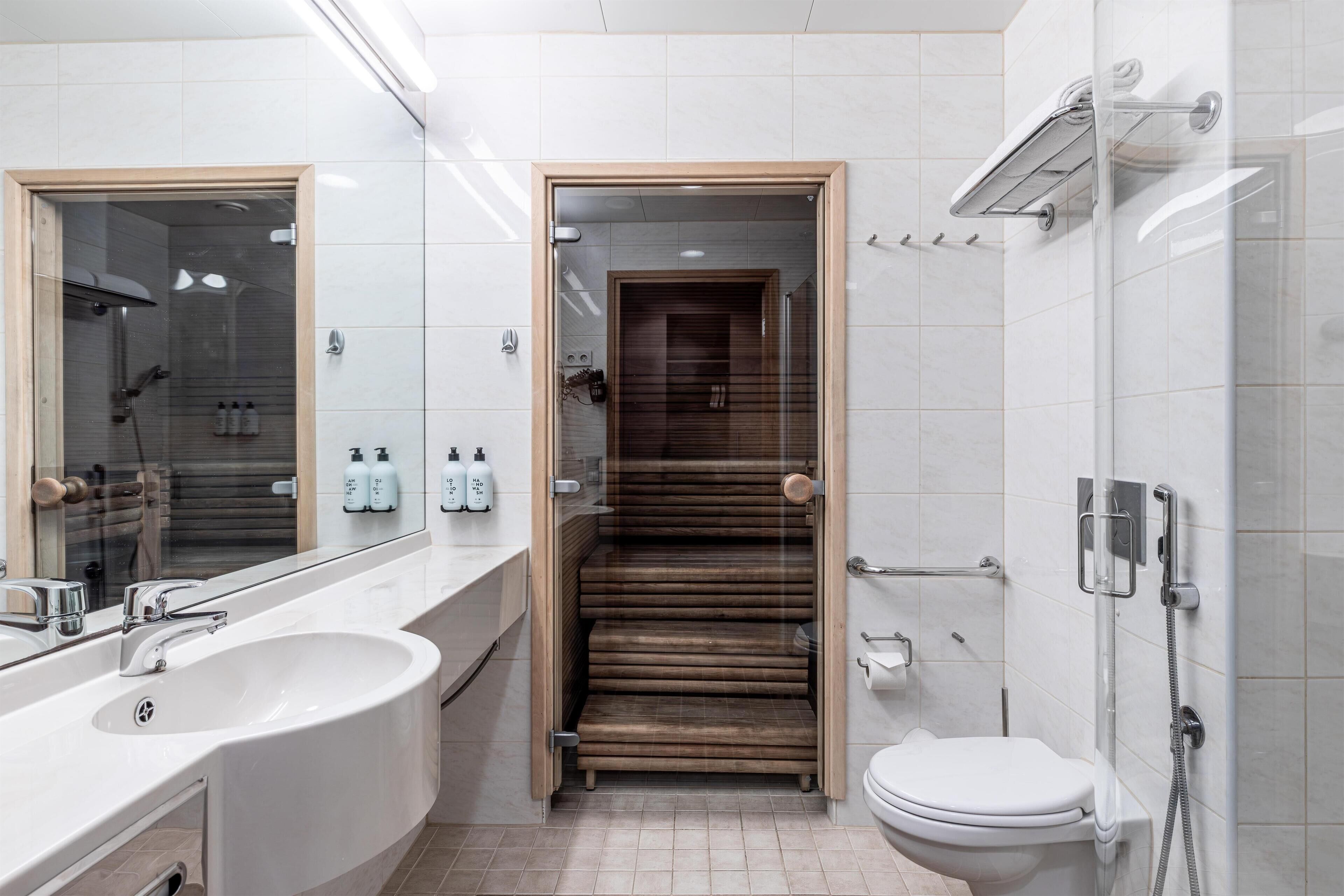 Un baño moderno con lavamanos grande, espejo, ducha y retrete.