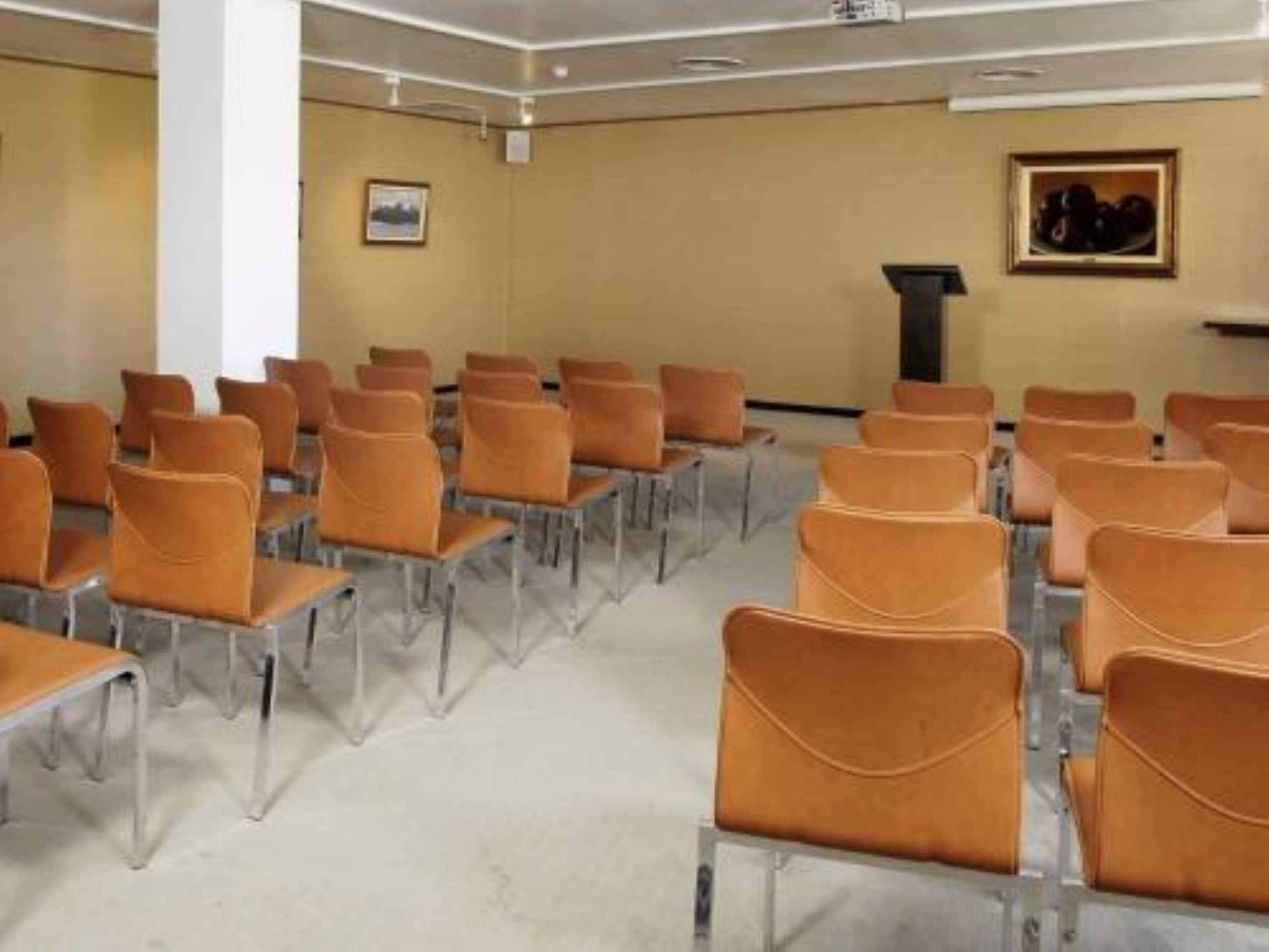 A conference room with rows of chairs and a podium.