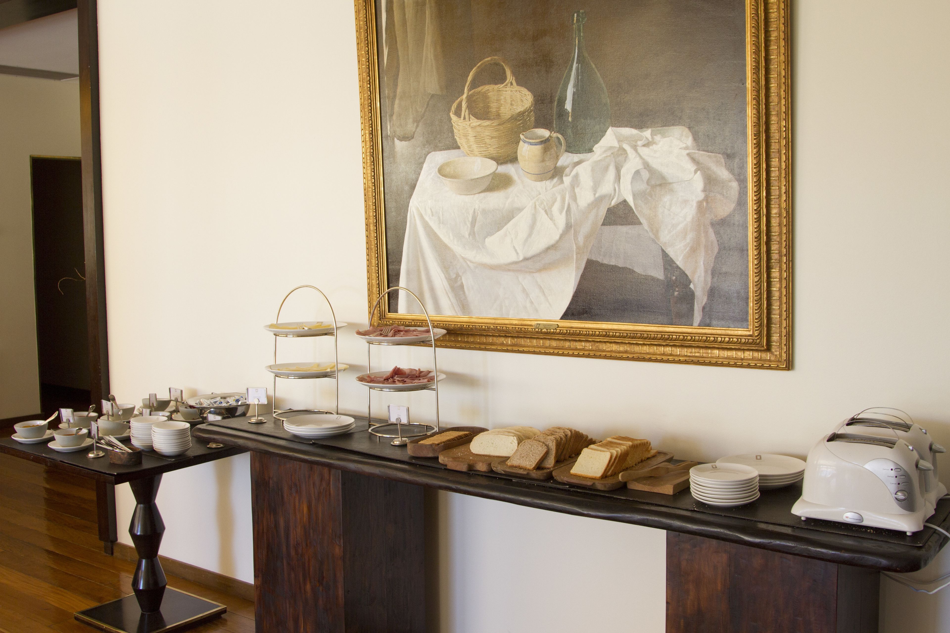 A buffet setup with various food items and a painting above.