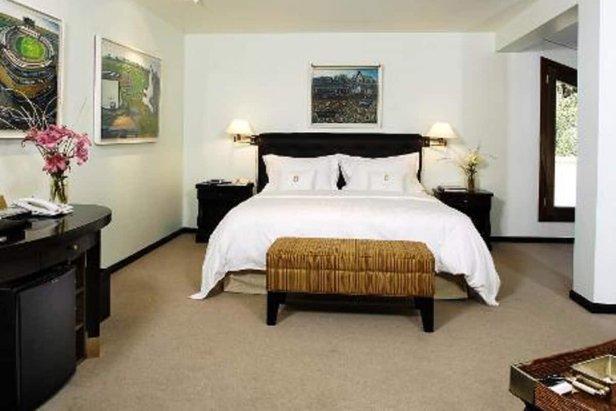 Une chambre à coucher avec un grand lit, deux tables de chevet, une commode, un bureau et une chaise.