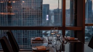 A dining table set for two with a cityscape view through large windows. - The Westin Guangzhou (Guangzhou)