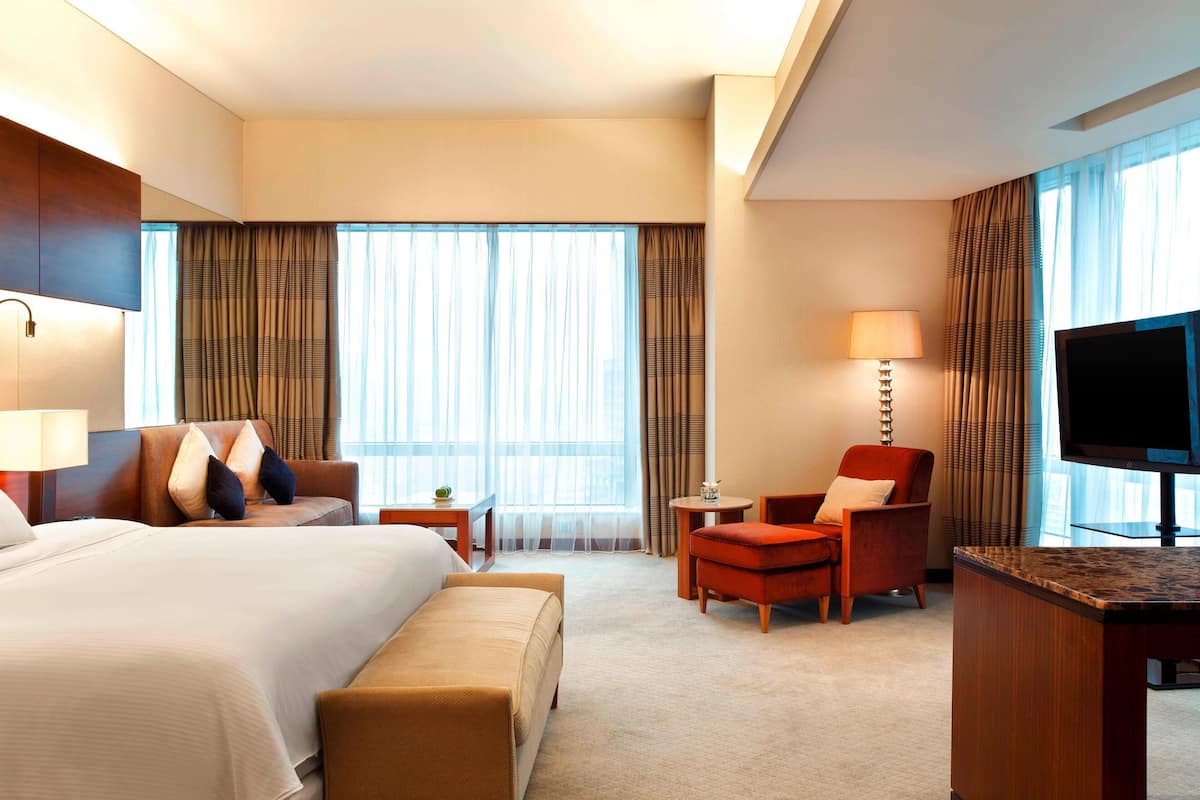 A hotel room with a large bed, a desk, a chair, and a TV.