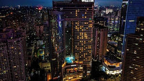 Un hotel de gran altura con un llamativo letrero 'WESTIN', rodeado de otros edificios altos en un paisaje urbano nocturno.