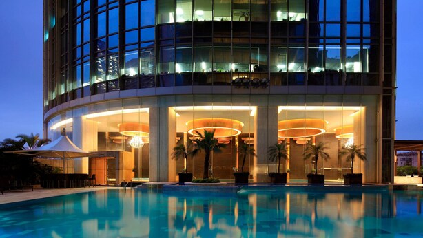 A modern hotel with a large pool, large windows, and a well-lit entrance. - The Westin Guangzhou (Guangzhou)
