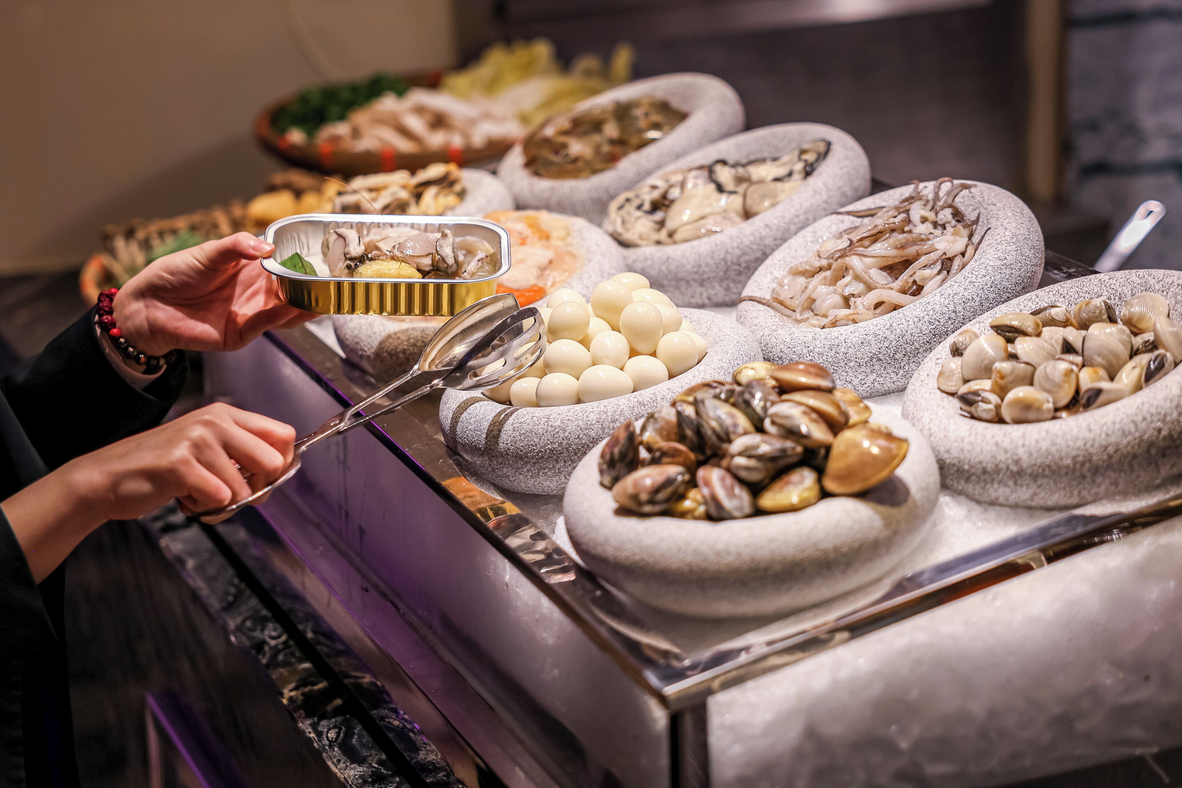 Un bufé con diversos platos de mariscos en cuencos de piedra.
