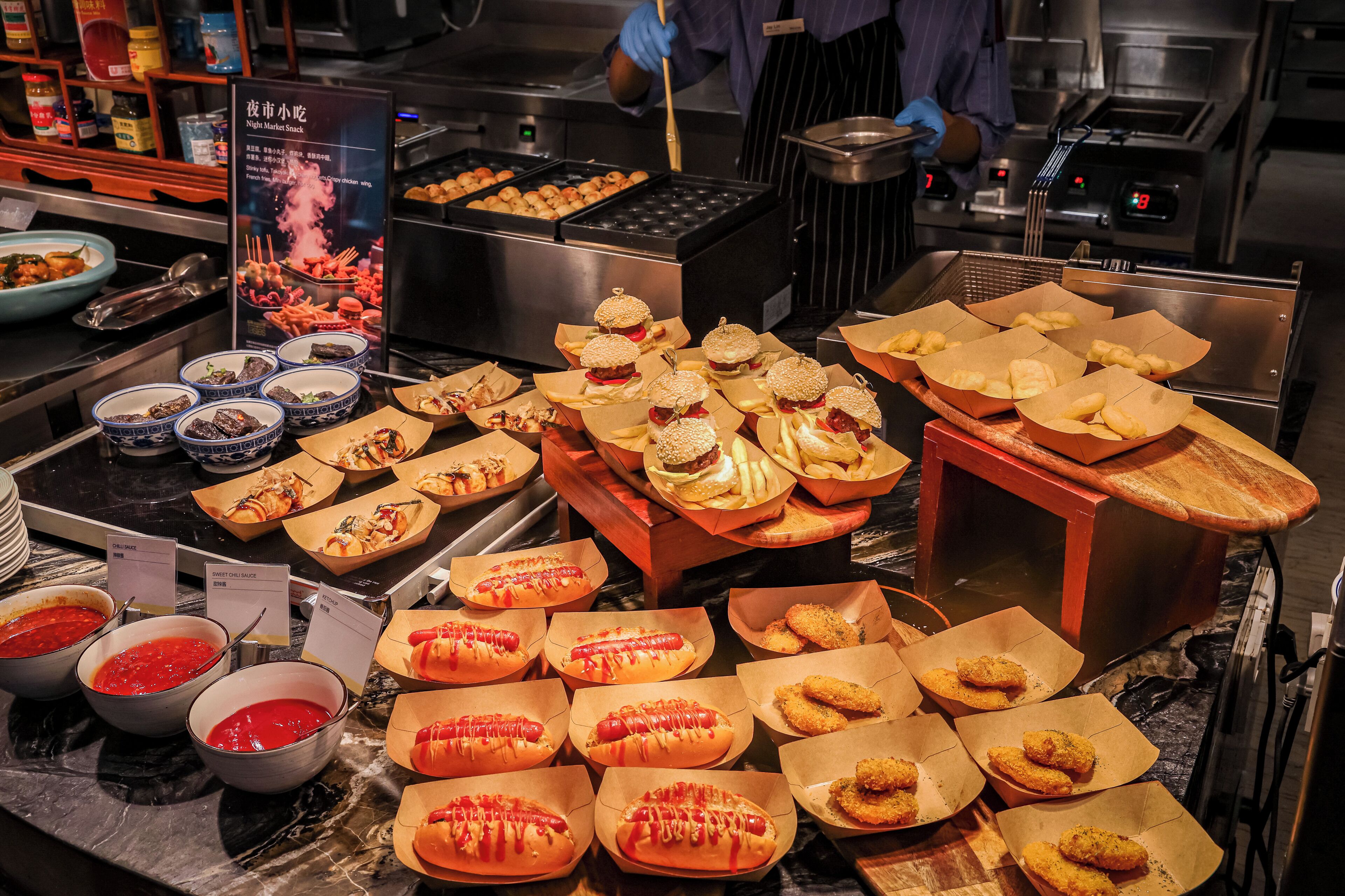 A buffet with various food items including hot dogs, burgers, and fried items.