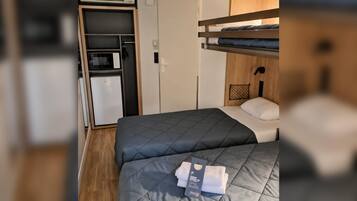 A compact room with a bunk bed, a small kitchenette, and a door leading to a closet.