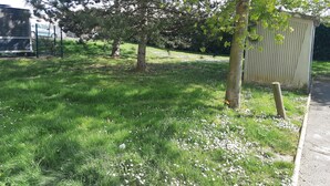 A grassy area with trees and a metal fence. - Premiere Classe Compiègne - Jaux (Jaux)