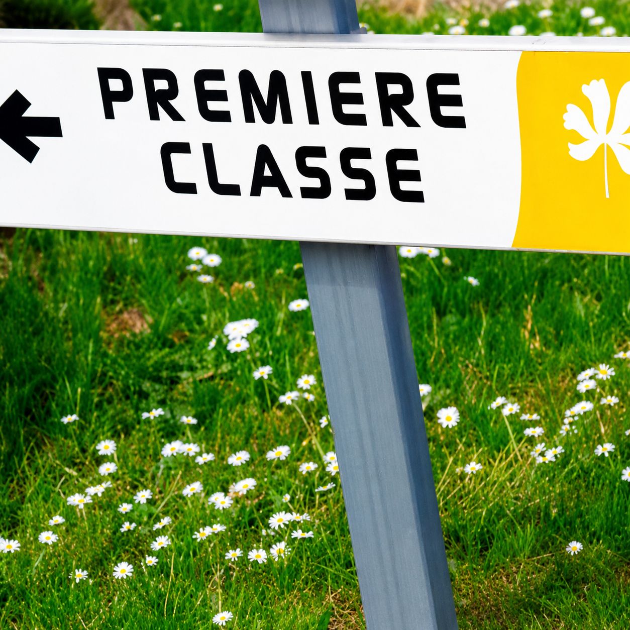 Una señal direccional con el texto 'PREMIERE CLASSE' y un símbolo de flor amarilla.