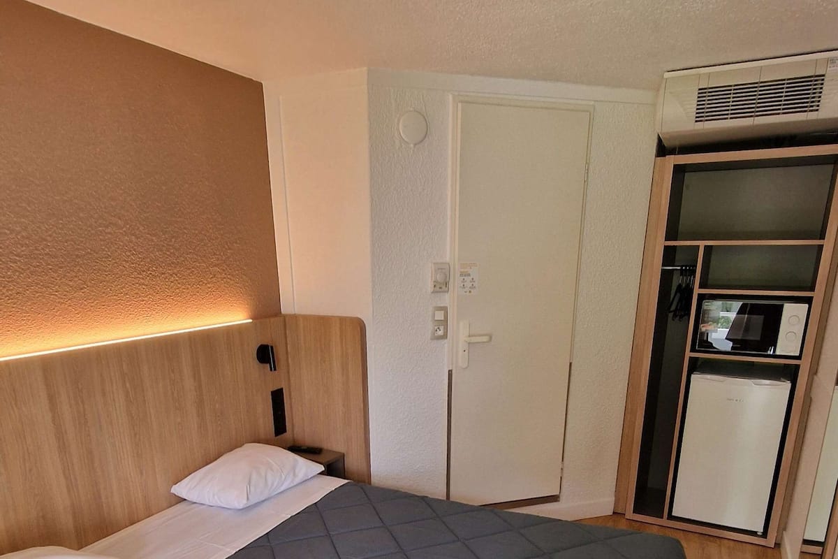 Una habitación de hotel con una cama grande, un armario, un microondas y un refrigerador.