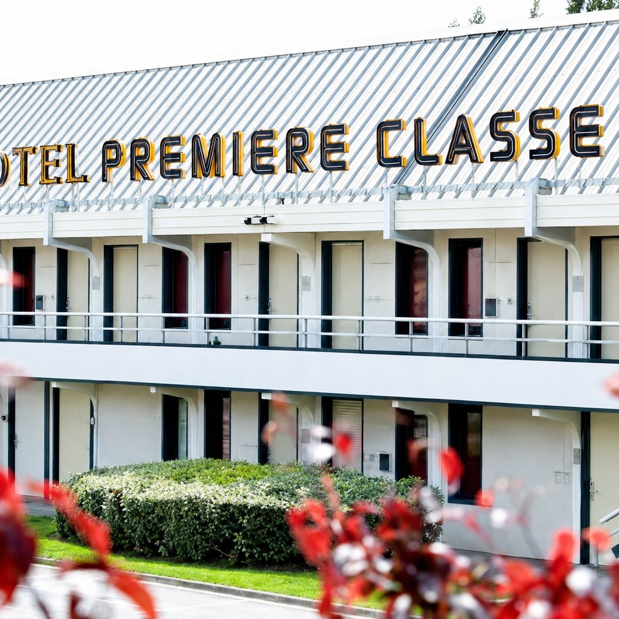 Un hotel con un cartel que dice 'HOTEL PREMIERE CLASSE' y una edificación de dos pisos con balcones.