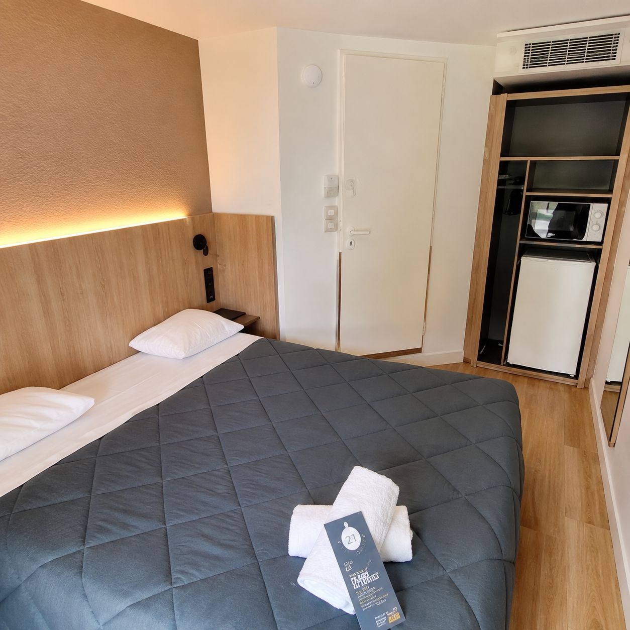 Una habitación de hotel con una cama, un armario y aire acondicionado integrado.