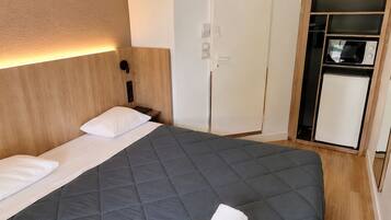 Una habitación de hotel con una cama, un armario y aire acondicionado integrado.