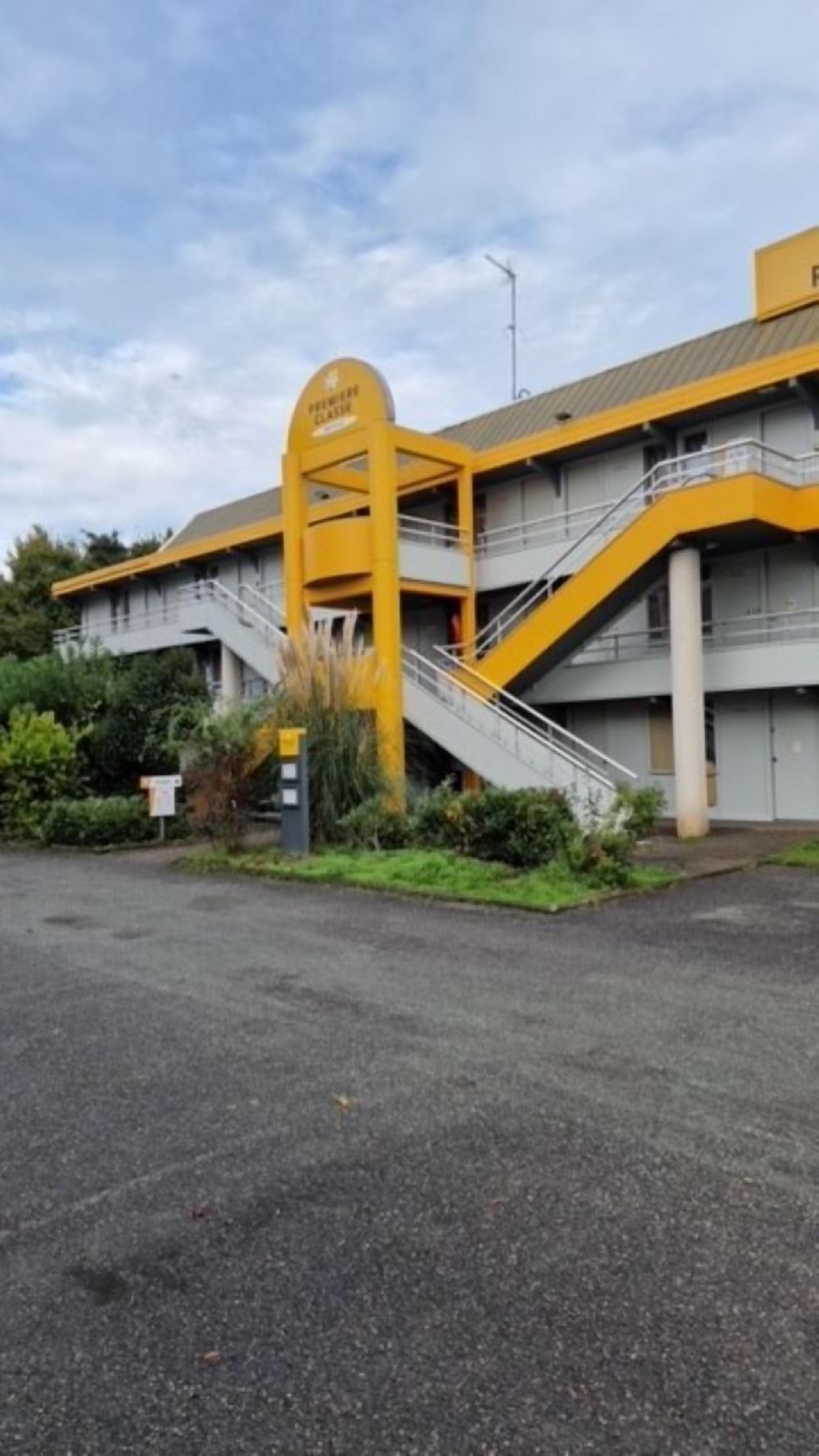 Un immeuble avec une entrée jaune et un escalier menant au deuxième étage.